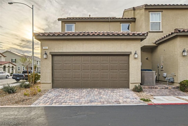 multi unit property with a tiled roof, decorative driveway, and stucco siding