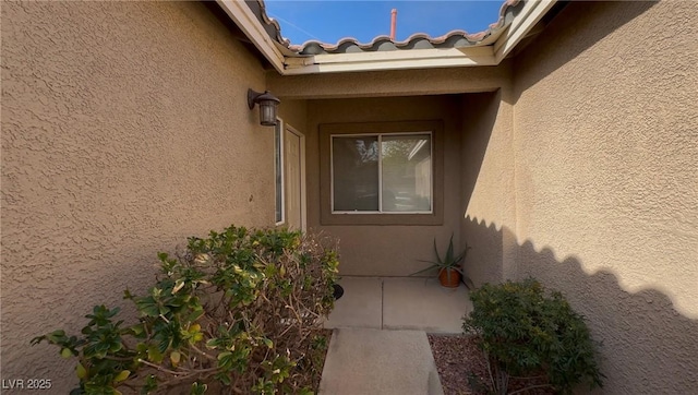 doorway to property featuring a tile roof and stucco siding