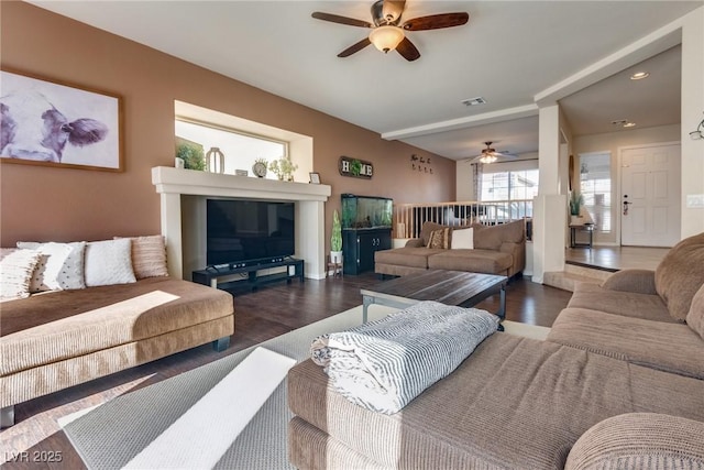 living room featuring dark wood-style flooring, visible vents, and a ceiling fan