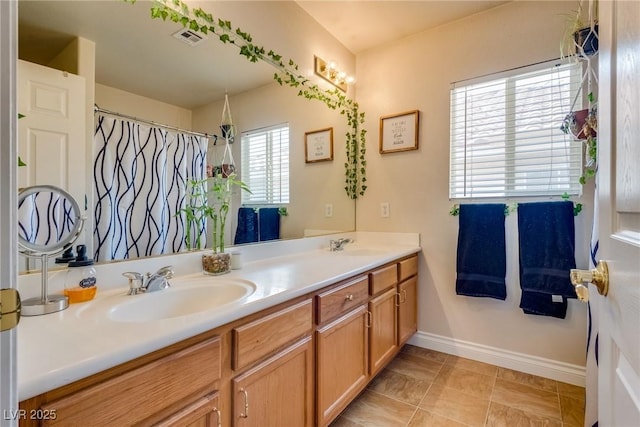 full bath featuring visible vents, a sink, baseboards, and double vanity