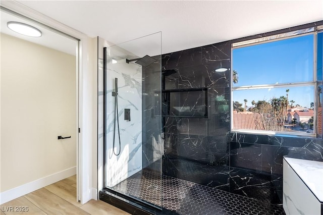 bathroom featuring wood finished floors, a marble finish shower, and baseboards