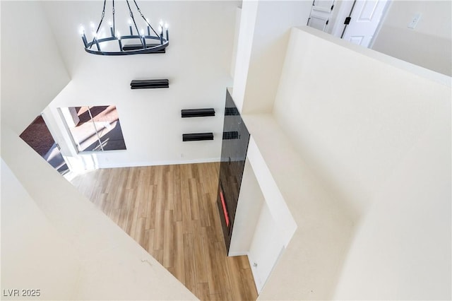 stairway featuring a chandelier, wood finished floors, and baseboards