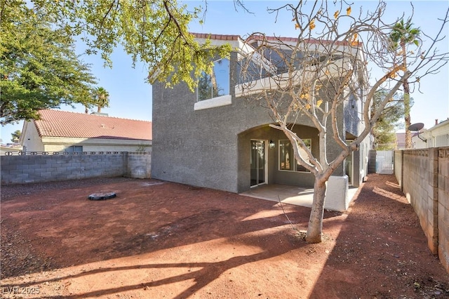 rear view of property with a fenced backyard, a patio, and stucco siding