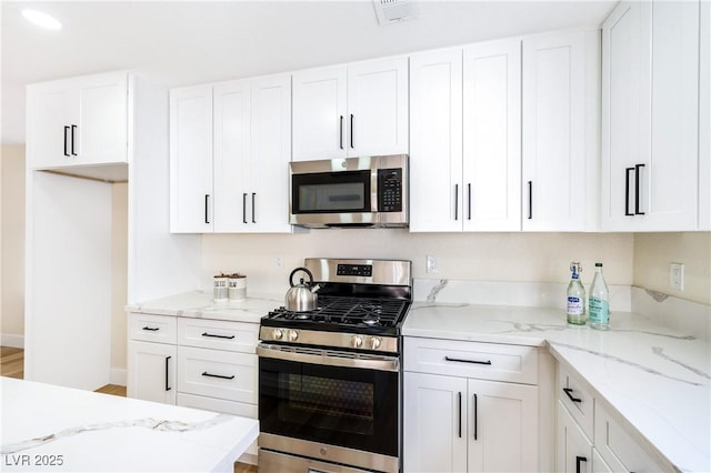 kitchen with appliances with stainless steel finishes, white cabinetry, and light stone countertops