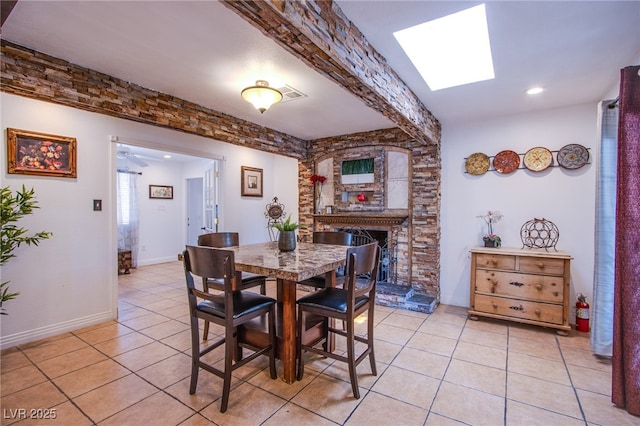 dining room featuring visible vents, a fireplace, baseboards, and light tile patterned flooring