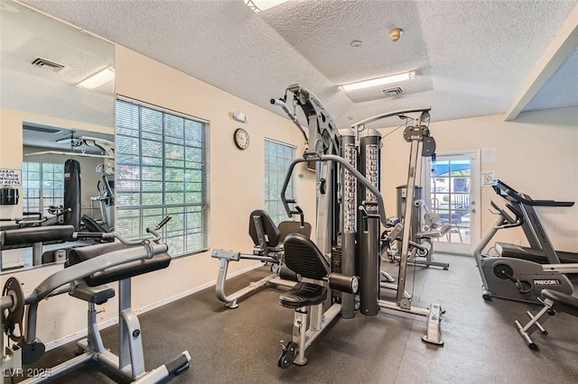 workout area featuring visible vents, a textured ceiling, and baseboards