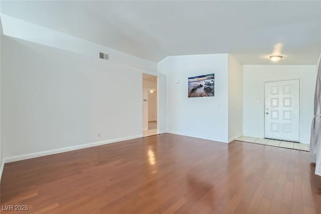 empty room with visible vents, baseboards, and wood finished floors