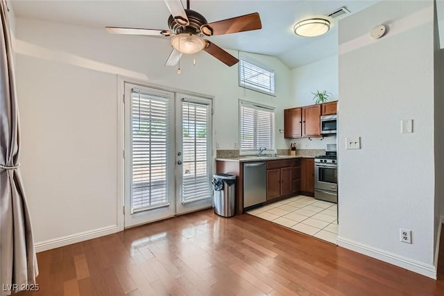 kitchen with stainless steel appliances, lofted ceiling, light countertops, and light wood finished floors