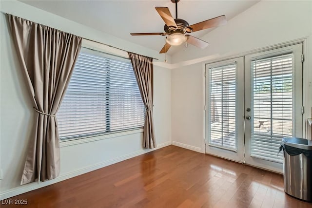 spare room featuring french doors, wood finished floors, a ceiling fan, and baseboards