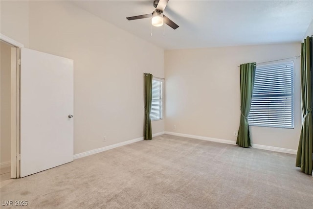 empty room with lofted ceiling, a wealth of natural light, a ceiling fan, and light colored carpet