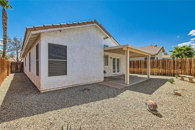 back of house featuring stucco siding, a fenced backyard, a tiled roof, and a patio