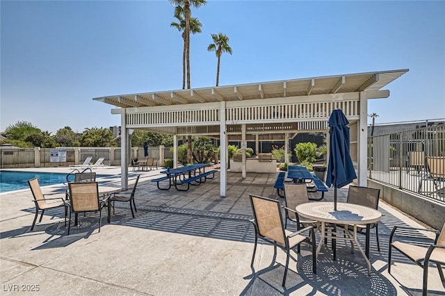 view of patio with a community pool, fence, and a pergola