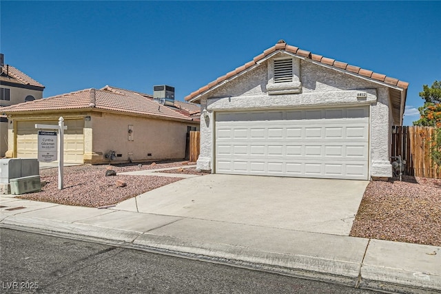 view of front facade featuring concrete driveway, fence, a tiled roof, and stucco siding