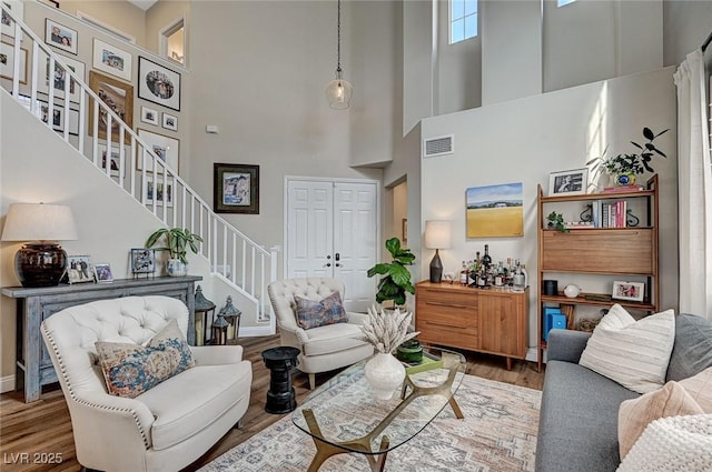 living room with baseboards, stairs, visible vents, and wood finished floors