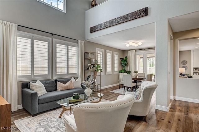 living room featuring french doors, a high ceiling, wood finished floors, and baseboards