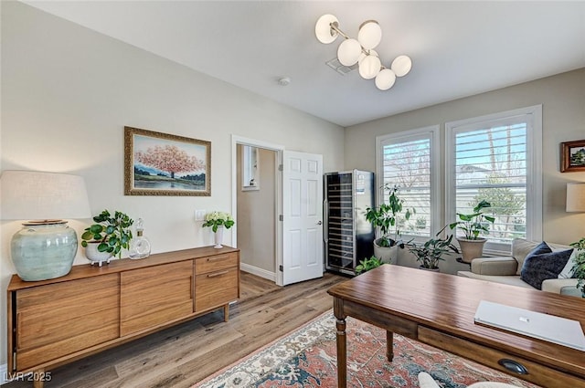 office with wine cooler, light wood-style flooring, a notable chandelier, visible vents, and baseboards