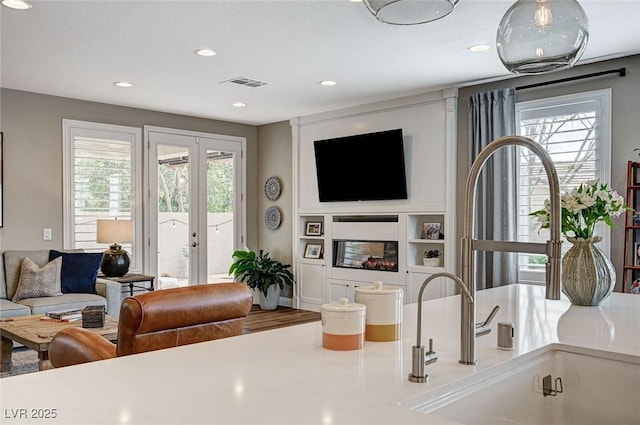 living room featuring recessed lighting, visible vents, french doors, and a glass covered fireplace