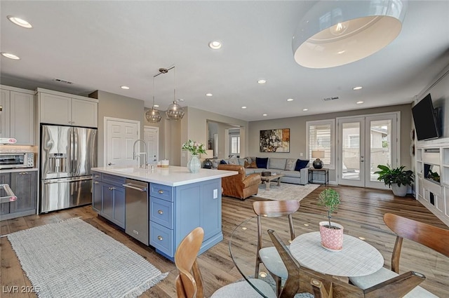 kitchen with white cabinets, open floor plan, light countertops, appliances with stainless steel finishes, and an island with sink