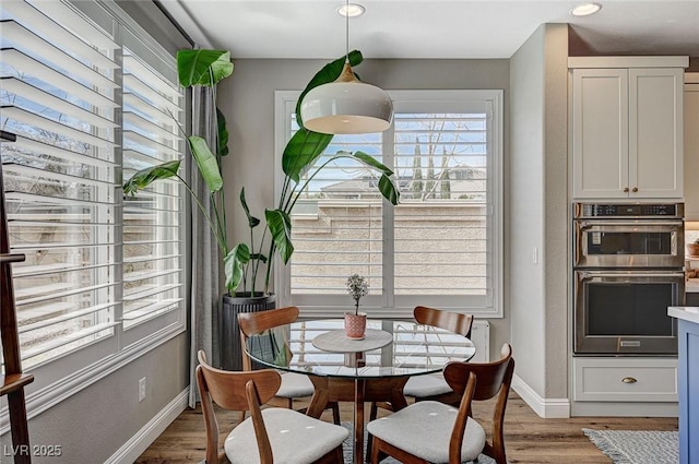 dining space with baseboards and light wood finished floors