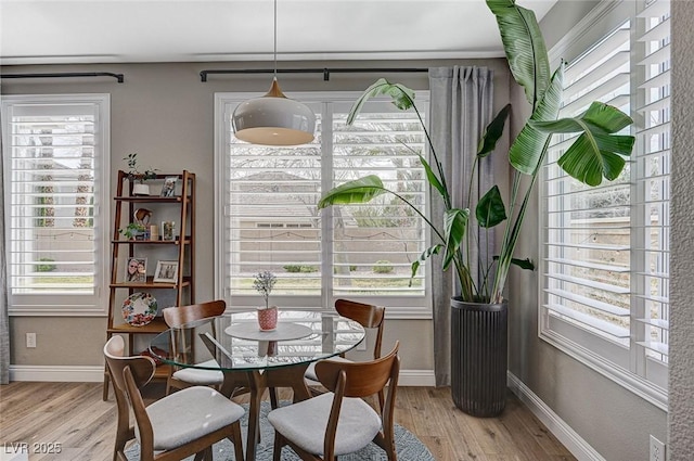 dining space featuring light wood-style flooring and baseboards