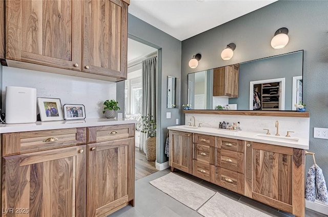 bathroom with double vanity, a sink, and a walk in closet