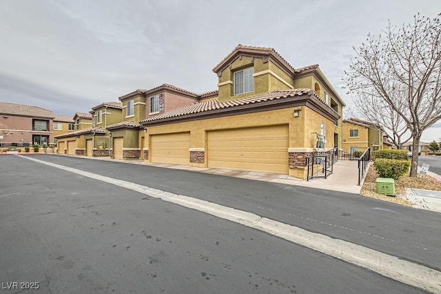 townhome / multi-family property with a tile roof, a residential view, and stucco siding