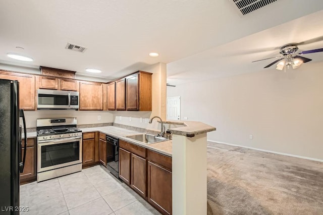 kitchen featuring black appliances, a peninsula, a sink, and visible vents