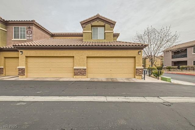 view of front facade featuring a garage, a tiled roof, and stucco siding