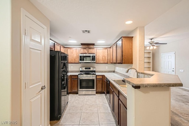 kitchen featuring visible vents, a peninsula, black appliances, a sink, and light tile patterned flooring