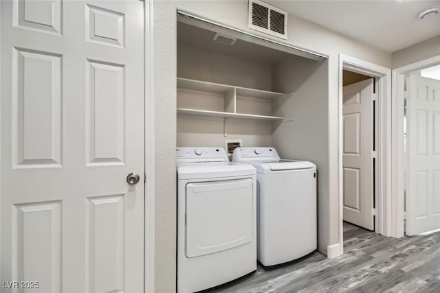 laundry room with laundry area, visible vents, light wood finished floors, and washing machine and clothes dryer