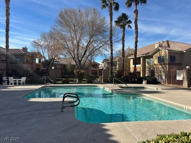 pool featuring a patio, fence, and a residential view