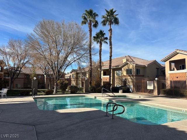 pool with a patio area, fence, and a residential view