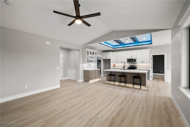 kitchen with a sink, white cabinetry, light wood-style floors, appliances with stainless steel finishes, and light countertops