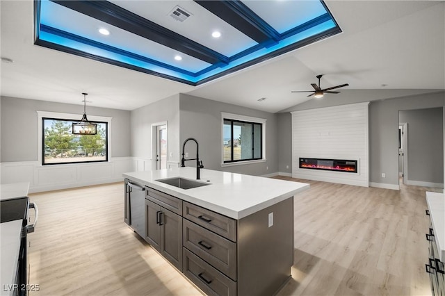 kitchen featuring visible vents, a sink, a fireplace, light wood finished floors, and dishwasher