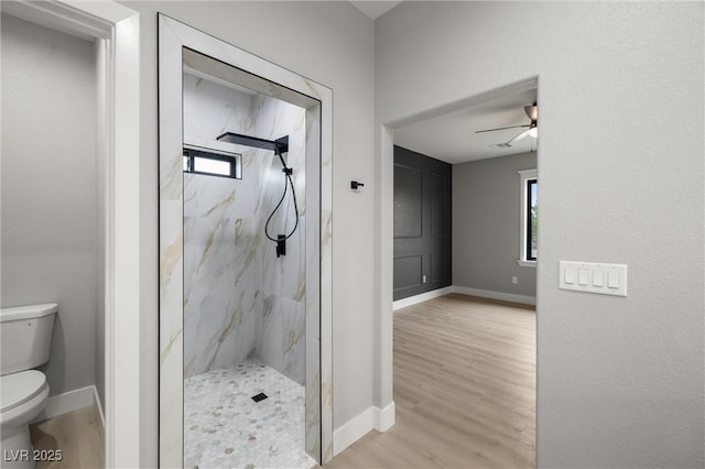 full bathroom featuring a marble finish shower, baseboards, toilet, and wood finished floors