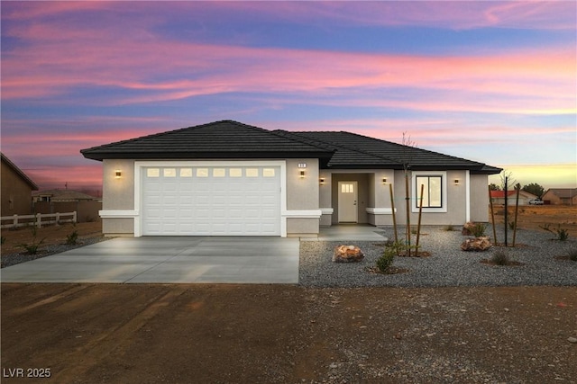 view of front facade featuring a garage, fence, driveway, and stucco siding