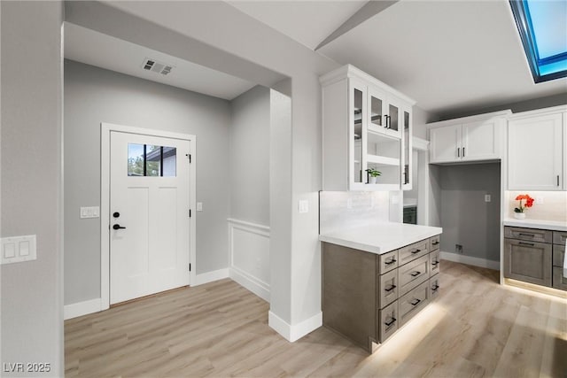 entryway featuring light wood-style flooring, a skylight, baseboards, and visible vents