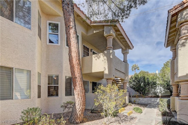 view of side of home with a balcony and stucco siding