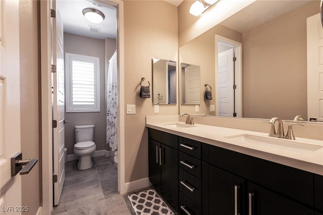 bathroom featuring double vanity, a sink, toilet, and baseboards