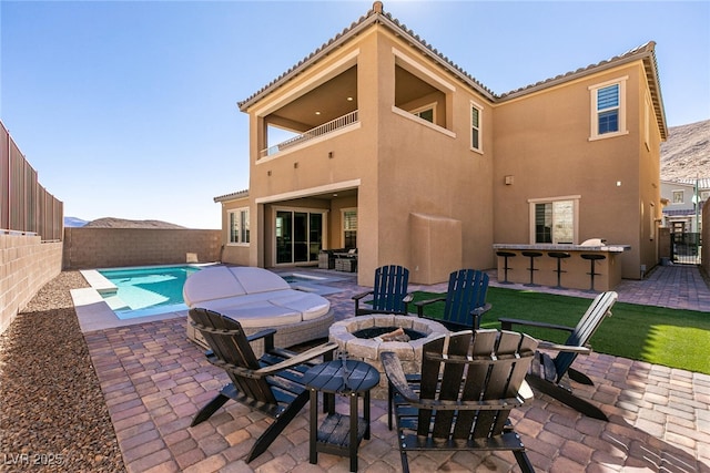 back of property with outdoor dry bar, a patio, an outdoor fire pit, and stucco siding