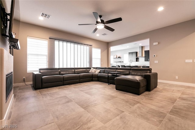 living area with a wealth of natural light, a glass covered fireplace, visible vents, and baseboards