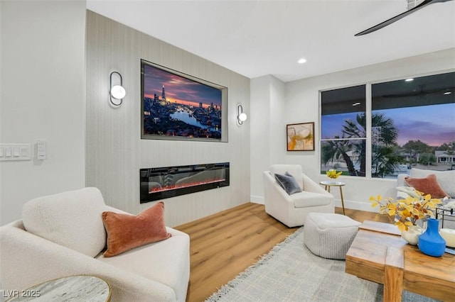 living room with recessed lighting, wood finished floors, and a glass covered fireplace