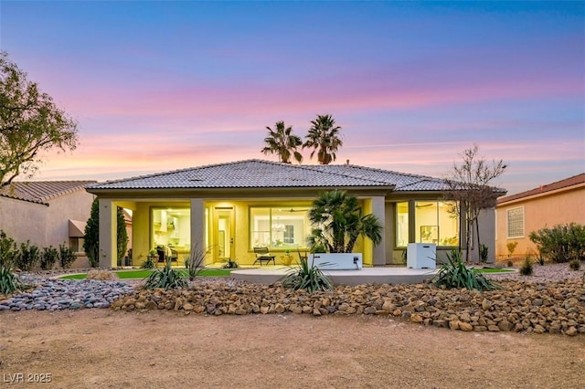 rear view of house featuring stucco siding, a tiled roof, and a patio