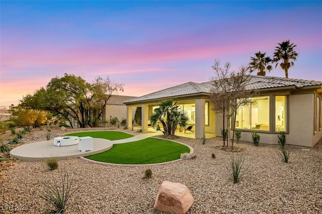 back of house featuring a yard, a tiled roof, a patio, and stucco siding