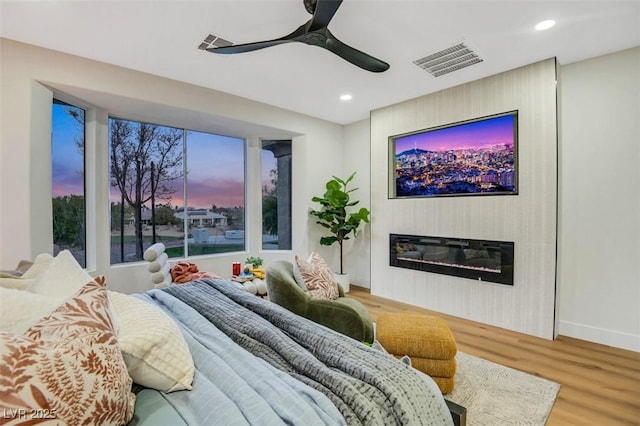 bedroom featuring recessed lighting, a ceiling fan, visible vents, light wood finished floors, and a glass covered fireplace