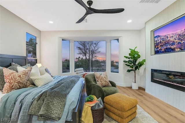 bedroom with ceiling fan, recessed lighting, visible vents, light wood finished floors, and a glass covered fireplace