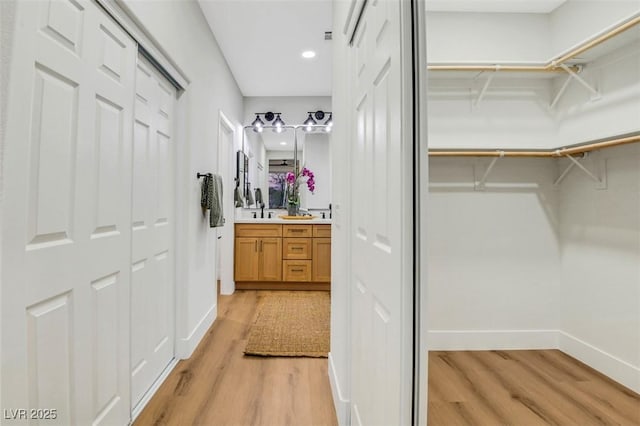 spacious closet featuring light wood-style flooring and a sink