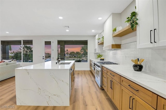 kitchen featuring open shelves, light stone counters, high end range, and white cabinets