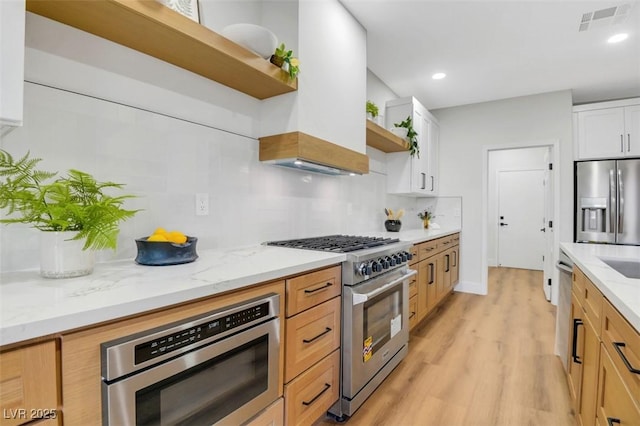 kitchen featuring appliances with stainless steel finishes, white cabinets, light stone counters, and open shelves