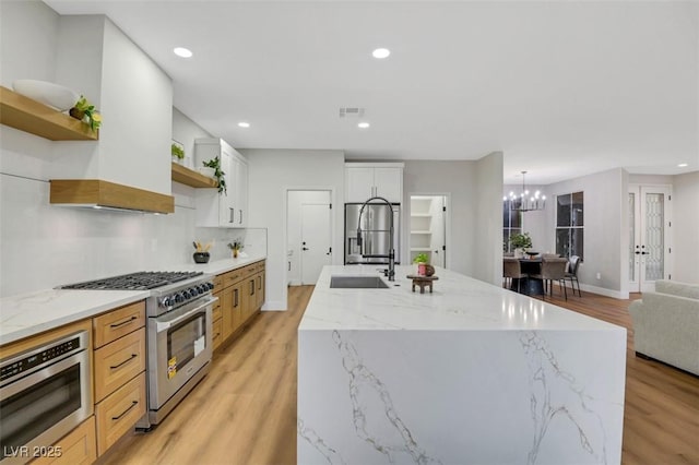 kitchen featuring a kitchen island with sink, open shelves, high end range, and white cabinets